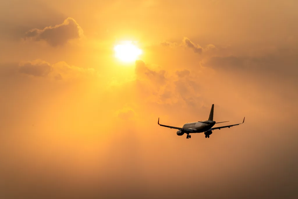 plane flying into a sunset